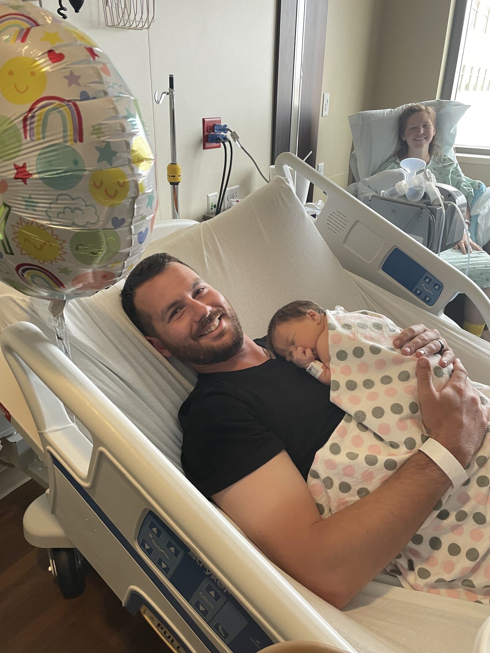 dad holding baby with mom in the back