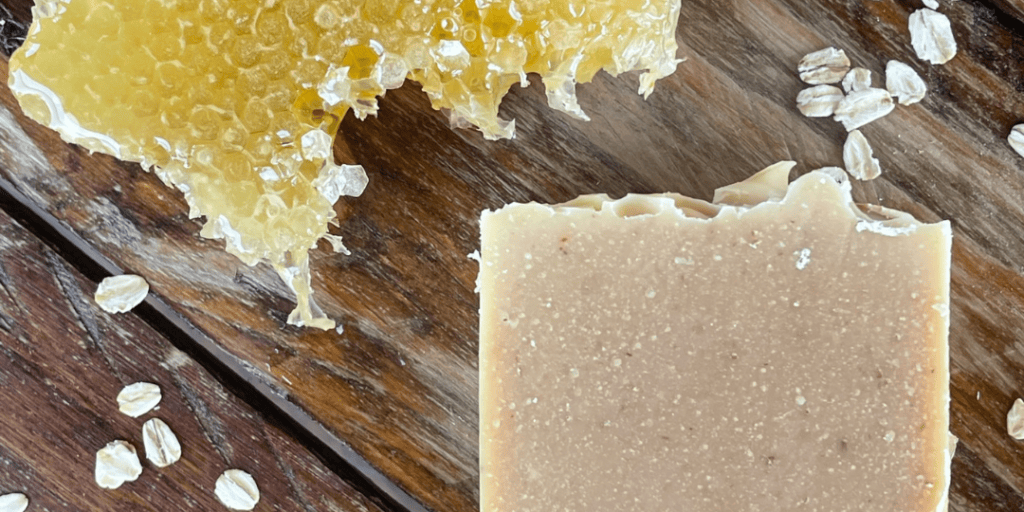 natural ingredients, oats and honey soap with a honeycomb and oats on a wood table