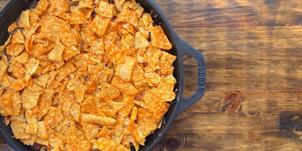 Homemade taco bake with chips on top in a cast iron skillet