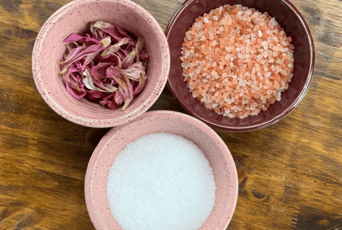 Bowls of pink Himalayan salt, Epsom salt, and dried peony petals for homemade bath soak