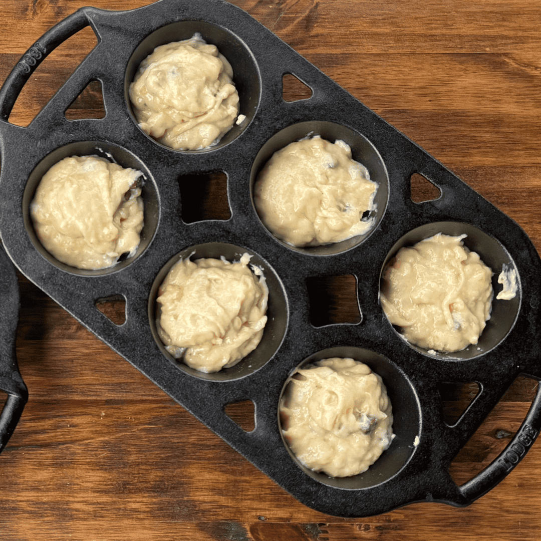 cast iron muffin pan with dough in them