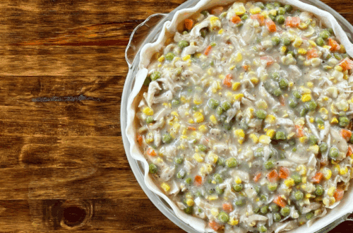 homemade chicken pot pie in a glass pie pan on a wooden table