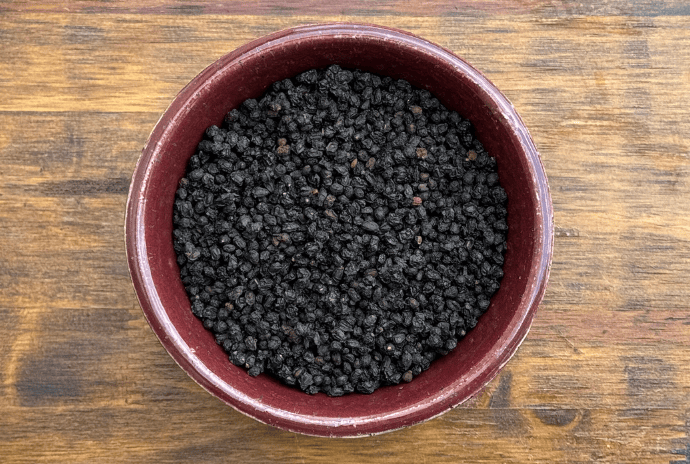 dried elderberries in a maroon bowl