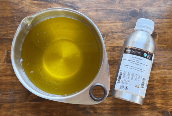 melted tallow and jojoba oil with frankincense essential oil on a wooden table