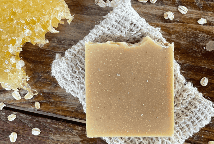 Oats and honey soap on a soap saver bag with honeycomb and sprinkled oatmeal beside it