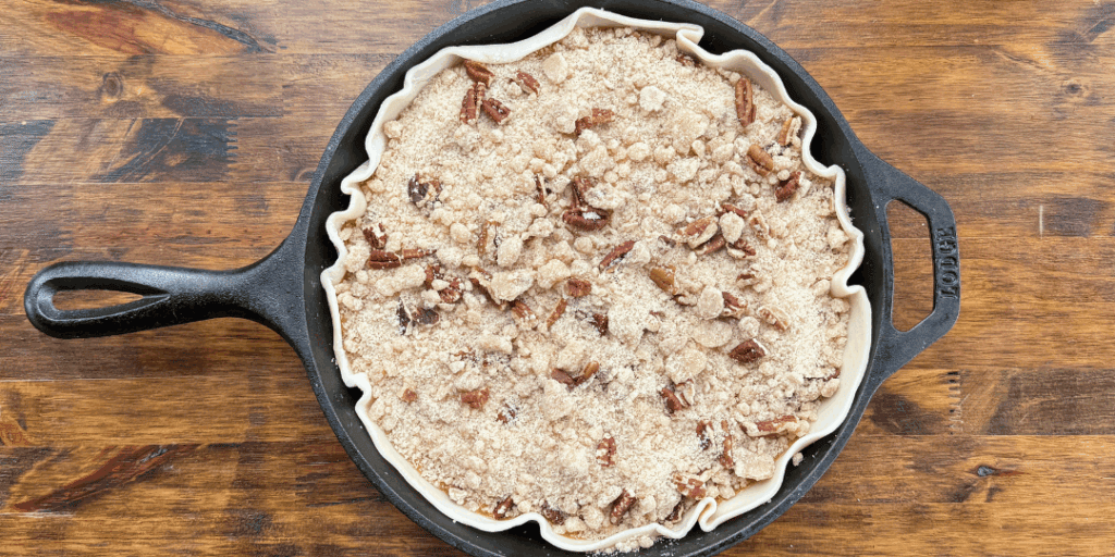 Pumpkin pie with pecan crumble topping baked in a cast iron skillet