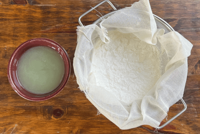 Greek yogurt strained in cheesecloth with whey separated in another bowl