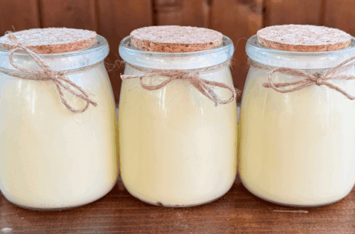 Three tallow balm jars placed side by side in a straight line on a wooden table