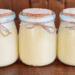 Three tallow balm jars placed side by side in a straight line on a wooden table