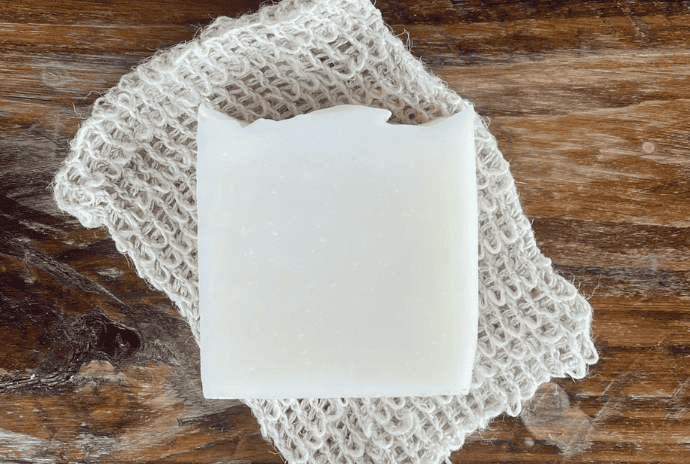 Simple white tallow soap bar on a textured soap saver bag