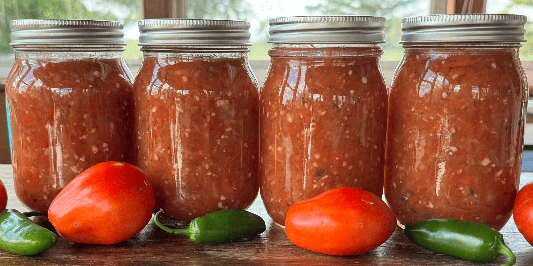 homemade canned salsa with garden fresh tomatoes and jalapenos on the table