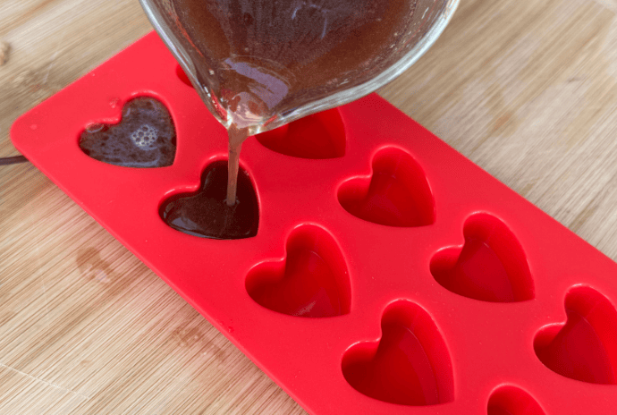 elderberry gummy mixture being poured into heart silicone molds
