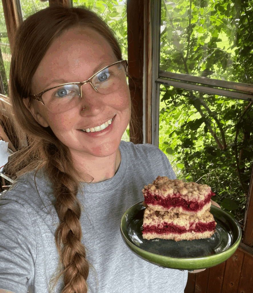 woman holding a plate of thimbleberry crumble bars