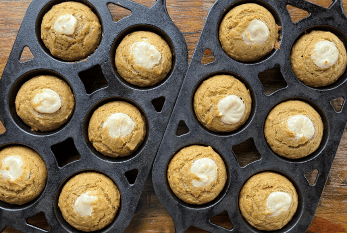 baked pumpkin cream cheese muffins in cast iron muffin pans
