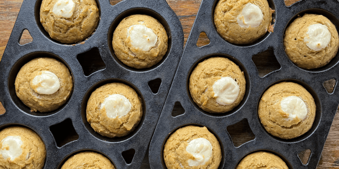 baked pumpkin cream cheese muffins in cast iron muffin pans