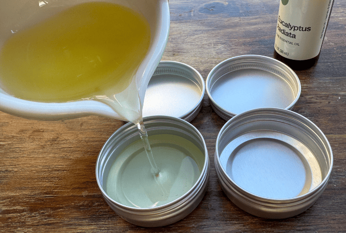 pouring homemade chest rub into 1 oz tins for colds
