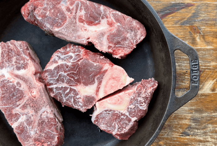 raw beef soup bones in a cast iron pan before roasting